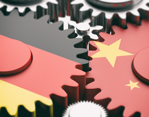 Zwei Zahnräder greifen ineinander. Das linke Zahnrad ist in den Farben der deutschen Flagge eingefärbt, das rechte Zahnrad in den Farben der chinesischen Flagge.