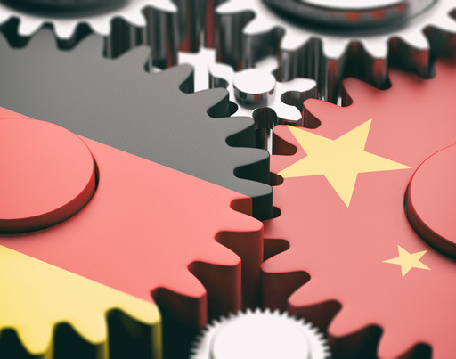 Zwei Zahnräder greifen ineinander. Das linke Zahnrad ist in den Farben der deutschen Flagge eingefärbt, das rechte Zahnrad in den Farben der chinesischen Flagge.
