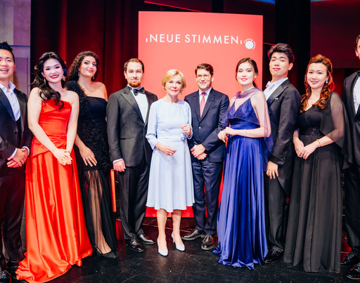 - Liz Mohn, Präsidentin des Wettbewerbs und Vorsitzende des Vorstands der Liz Mohn Stiftung, zusammen mit Alexander Neef, Vorsitzender der Jury der NEUEN STIMMEN, und den Finalist:innen des Wettbewerbs 2026.