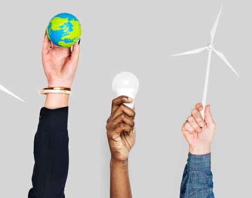 Several people have raised their arms and are holding various symbols for climate protection and sustainability in their hands: A wind turbine, a small model of the Earth, a LED light bulb, another wind turbine and an energy-saving light bulb.