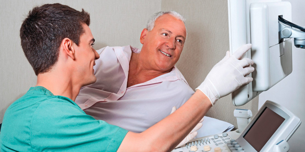 Ein Arzt zeigt einem Patienten auf einem Bildschirm Ergebnisse seiner Untersuchung zur Krebsfrüherkennung.