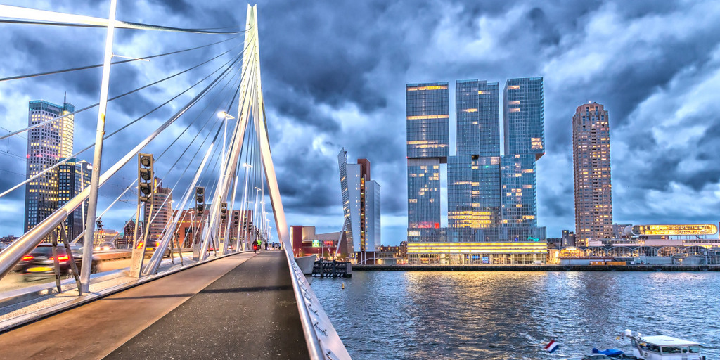 A bridge and several high rise buildings at night time in the city of Rotterdam, Netherlands.