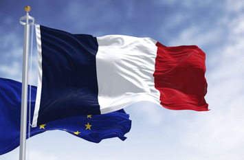 The flags of France and the European Union waving together on a clear day.