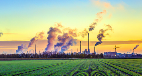 Dampfende Industrie vor grünem Feld