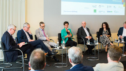 Podiumsdiskussion: folgendes Personen sitzen auf einem erhöhten Podium (von rechts nach links). Reiner Hoffmann, Sarah Ryglewski, Uwe Zimmermann, Dr. Kirsten Witte, Dr. Kay Ruge, Helmut Dedy, Patrick H. Leusch.