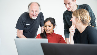 Ein Ausbilder zeigt seinen Schülern etwas am Computer.