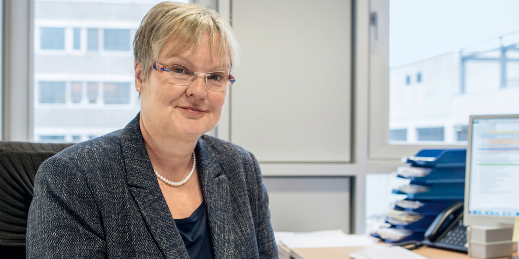 Sabine Krink, Europabeauftragte für Hagen und die Märkische Region, sitzt an ihrem Schreibtisch und lächelt in die Kamera.