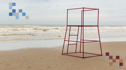 Weitläufiger Strand zu sehen und dem Meer im Hintergrund sowie einem roten Strandhochsitz aus Metall