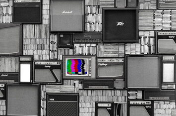 viele Fernseher alt neu an einer Wand