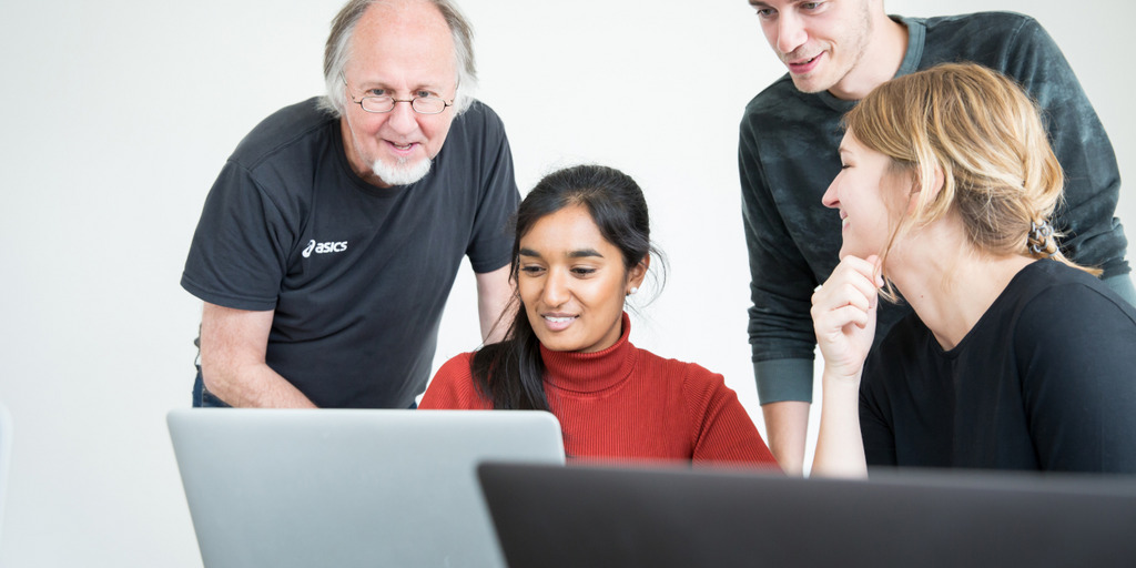 Ein Ausbilder zeigt seinen Schülern etwas am Computer.