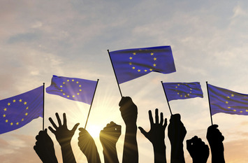 Silhouette of arms raised waving a European Union flag with pride