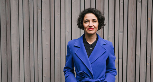 Anna-Lena von Hodenberg in einem blauen Mantel vor einer holzvertäfelten Wand.