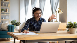 Frau mit Headset arbeitet am Laptop