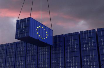 A freight contrainer with the EU flag hangs in front of many blue stacked freight containers