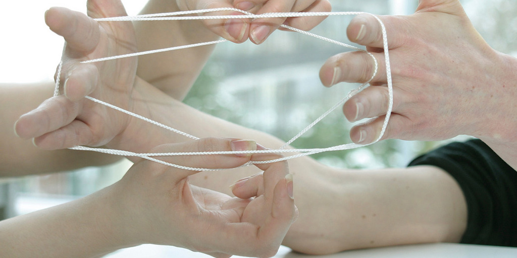 Hände, die ein Netz aus Fäden bilden, nach dem Motto: Gemeinsam stark
