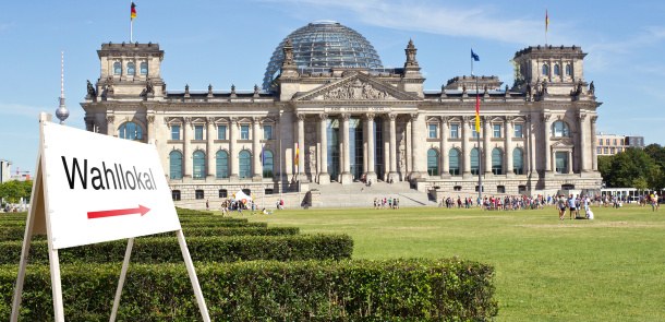 Vor dem Reichstagsgebäude in Berlin steht ein Schild, das die Richtung zu einem Wahllokal weist.